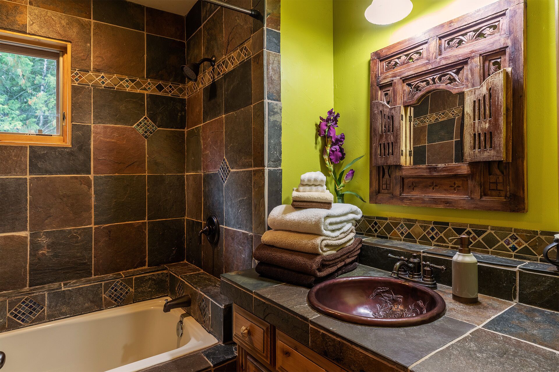 Un baño con bañera, lavabo con una pila decorativa y tocador con espejo.