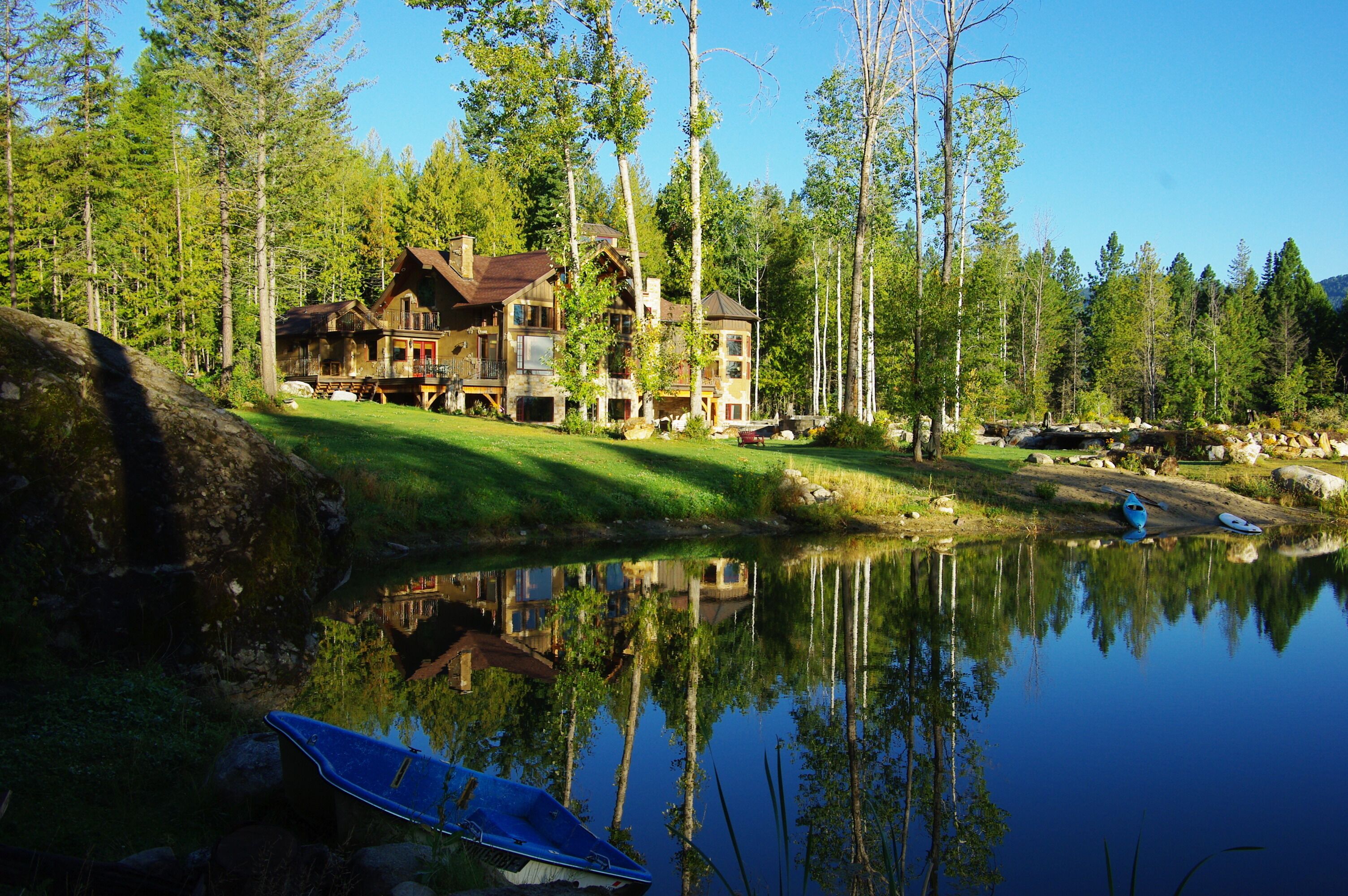 A lodge with a large wooden structure surrounded by a forest and a lake.