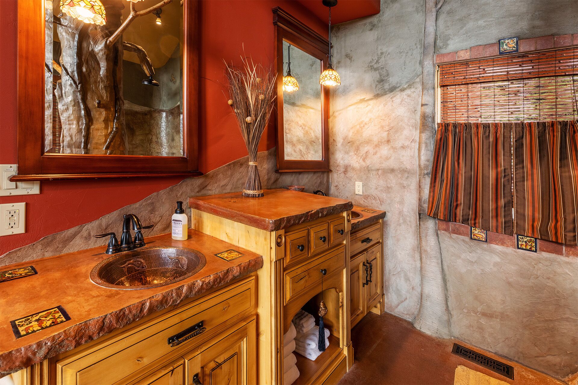 Een badkamer met een houten wastafelmeubel, een grote spiegel en een decoratief wandpaneel.