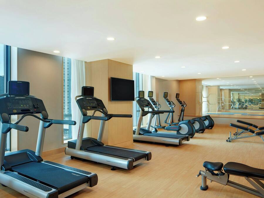 A gym with treadmills, a stationary bike, and a bench.