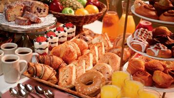 A breakfast buffet with pastries, fruits, and beverages.
