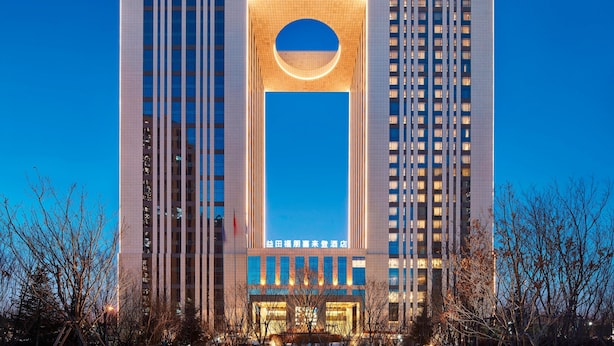 A modern hotel with a prominent vertical design, featuring a large illuminated entrance and a circular skylight. - Four Points By Sheraton Changchun, Hi-Tech Zone (Changchun)