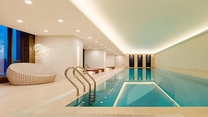 A modern indoor swimming pool with a clear water surface, a long bench along the side, and a unique perforated lounge chair. - Four Points By Sheraton Changchun, Hi-Tech Zone (Changchun)