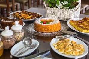 Una mesa con varios postres, entre ellos un pastel ring, una porción de pastel y un plato de rodajas de plátano.