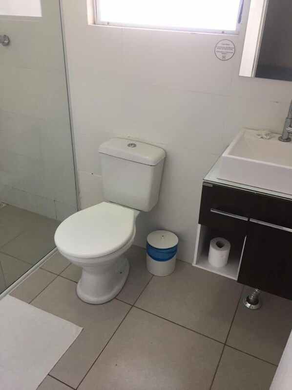 Un baño con inodoro, lavabo y un pequeño cubo de basura.