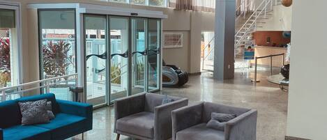 A spacious lobby with large windows, a reception desk, and multiple seating areas.