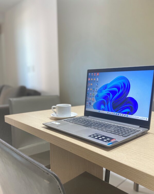 A laptop on a wooden table with a white cup beside it. - Beach Class Fortaleza By AM (Fortaleza)