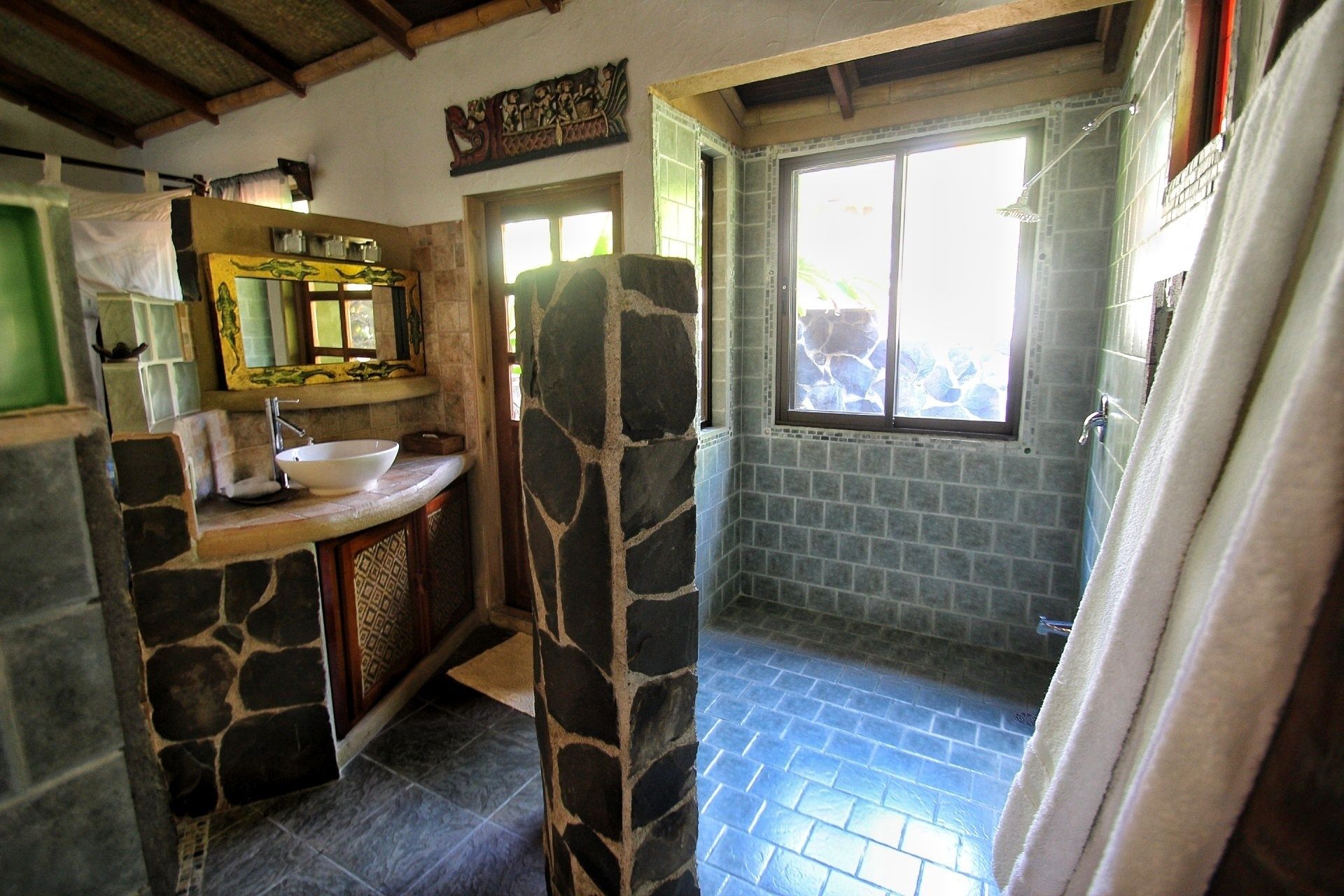 Une salle de bain avec un lavabo en pierre, un miroir et une fenêtre.