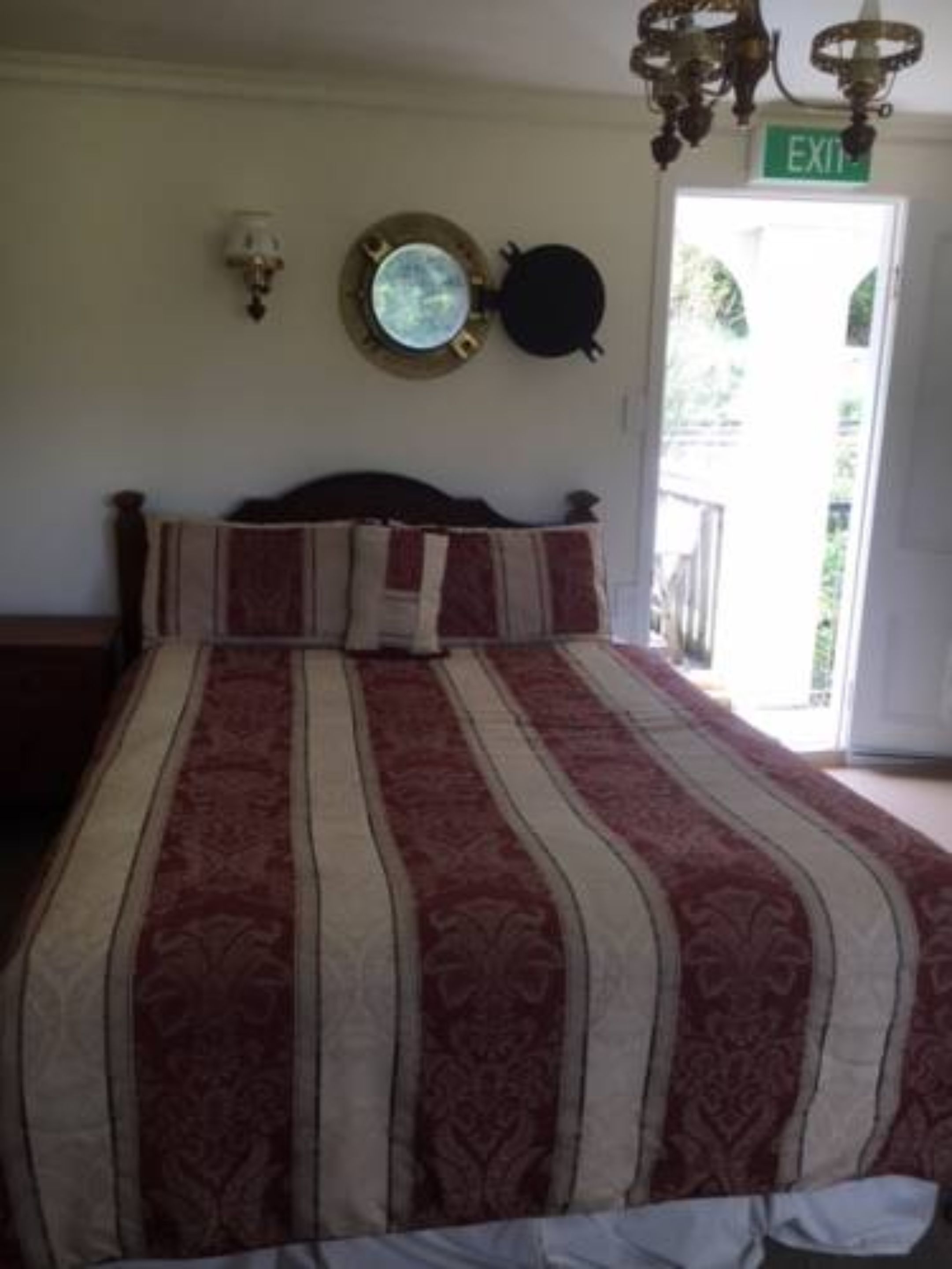 A bedroom with a large bed, a round mirror, a clock, and an exit sign.