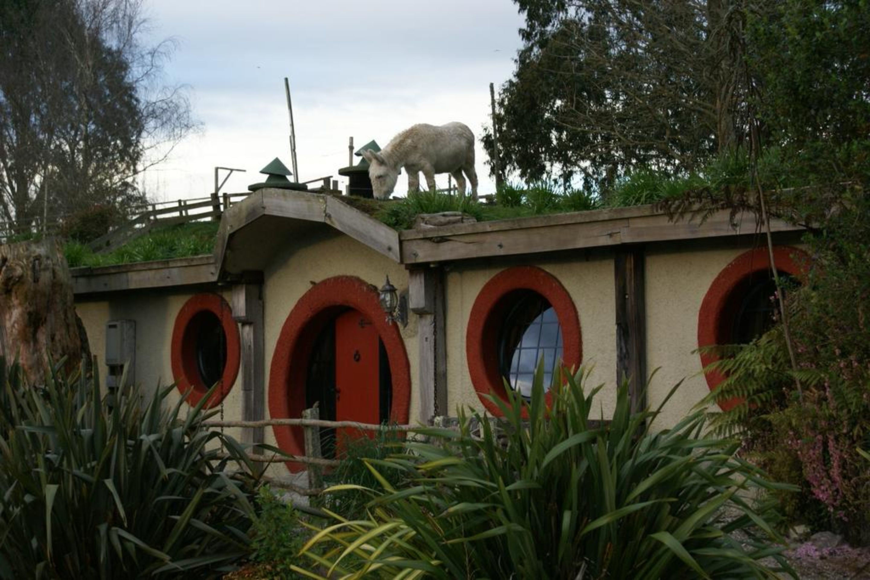 A building with red arched doors and a white animal statue on top.