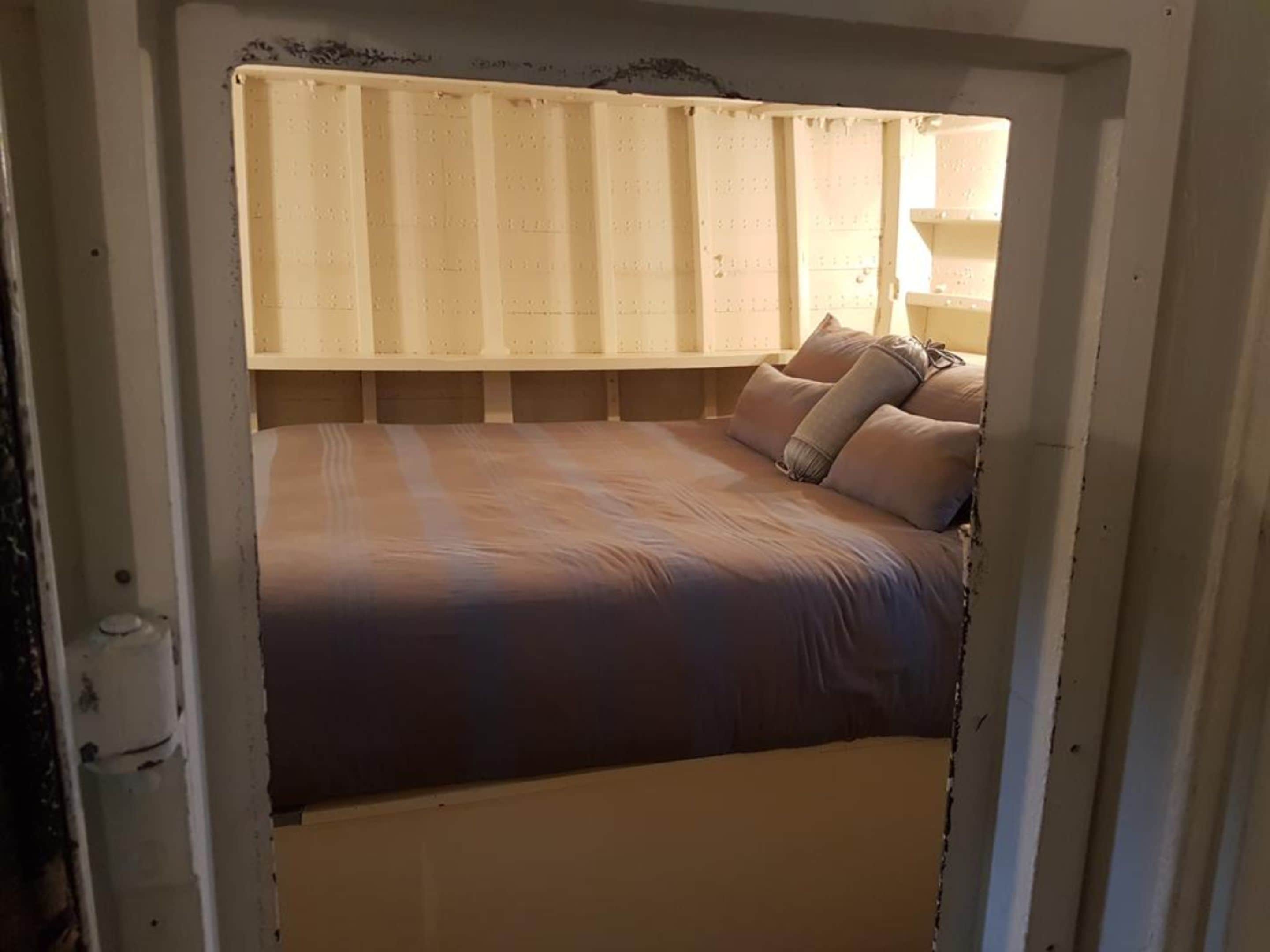 A bed with a headboard, pillows, and a blanket.