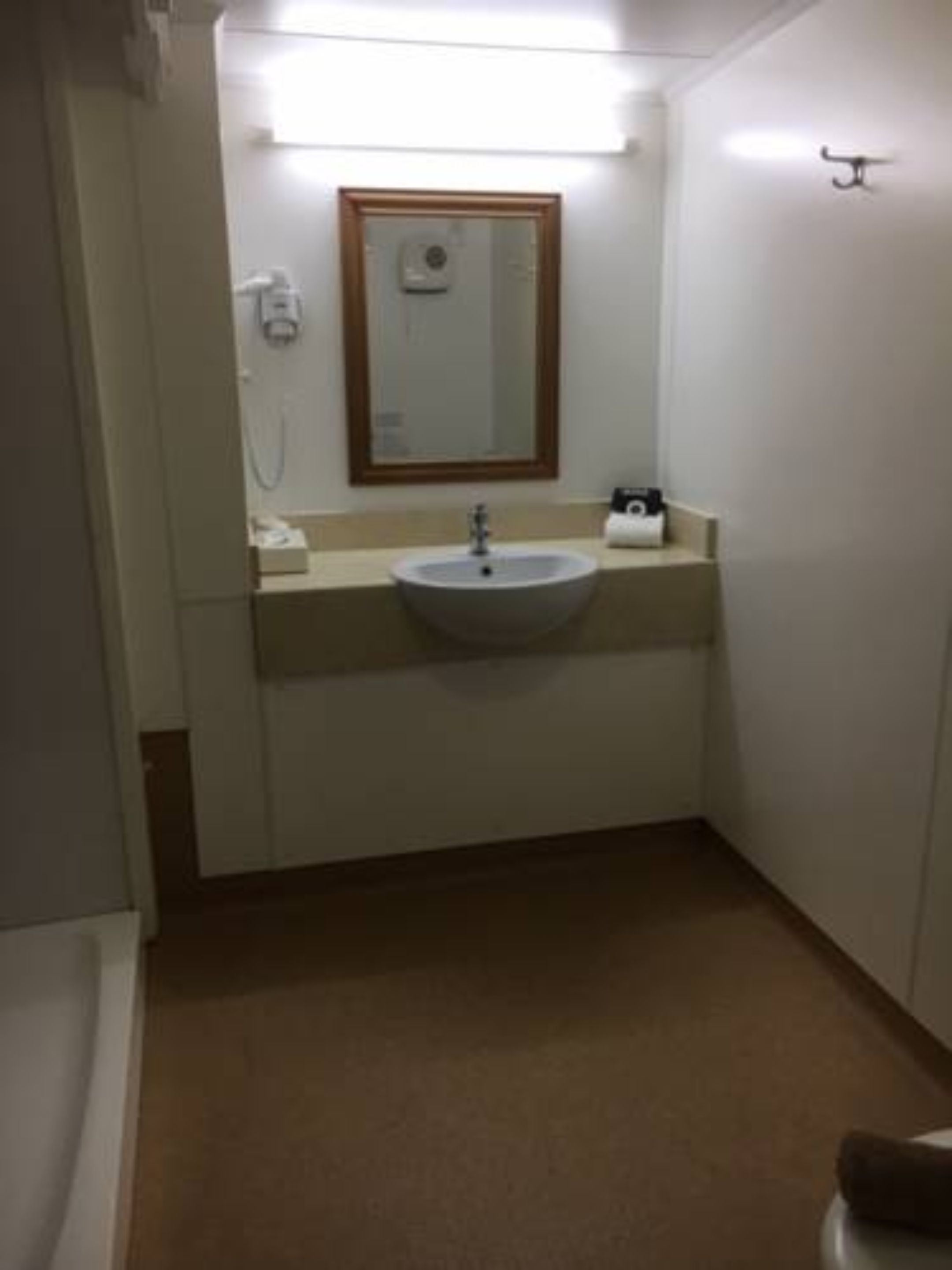 Ein kleines Badezimmer mit Waschbecken, Spiegel und Handtuchhalter.
