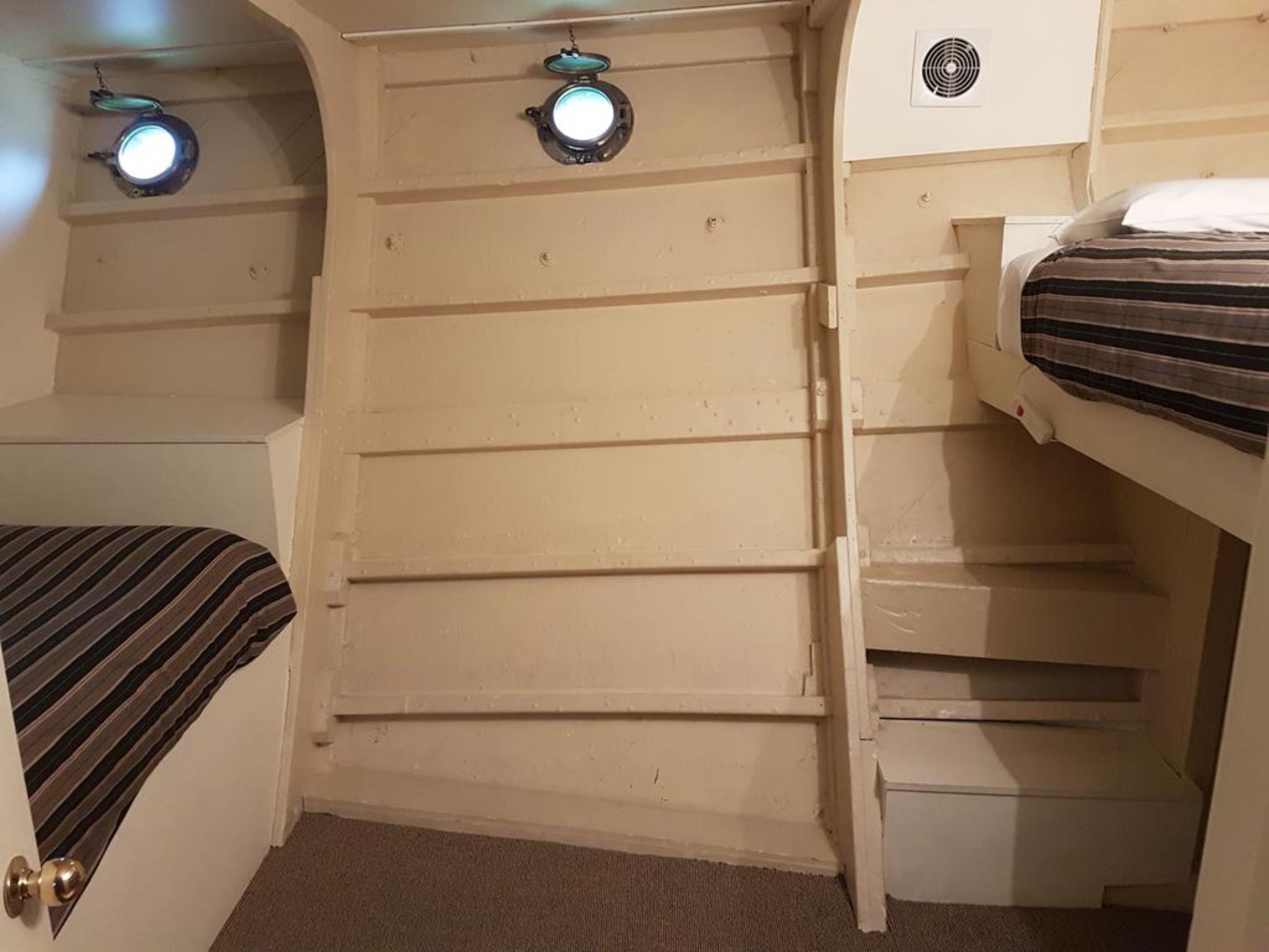 Een compacte, eenkamerhut met een stapelbed, twee kleine ramen met verlichting, en een ingebouwde airconditioning.