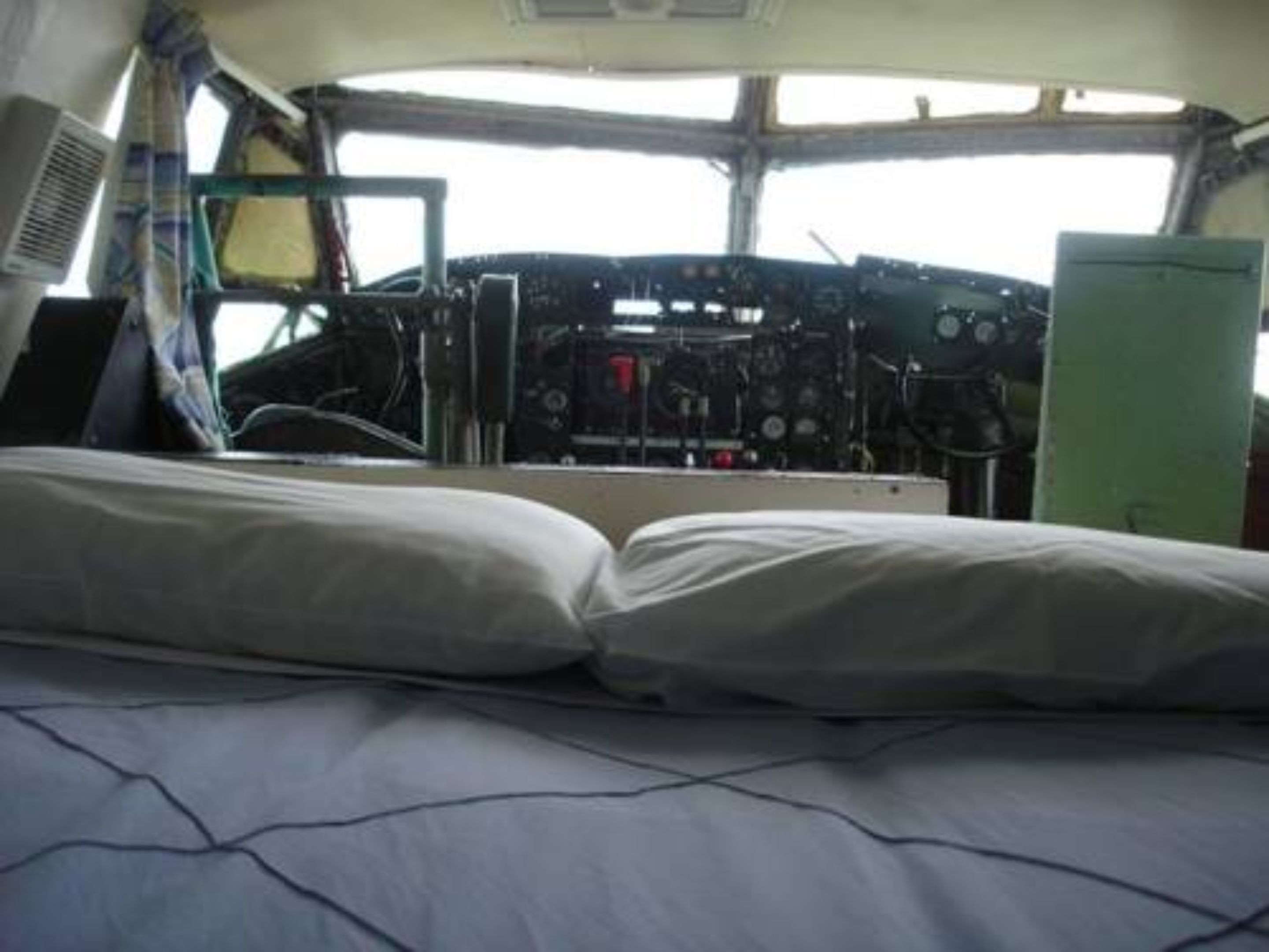 A cabin with a bed, a control panel, and a window.