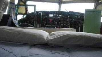 A cabin with a bed, a control panel, and a window.