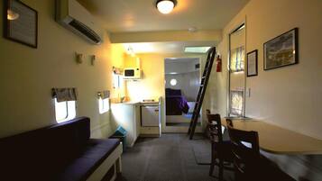 Une pièce de taille modeste comprenant un lit, une petite kitchenette, un bureau et une chaise.