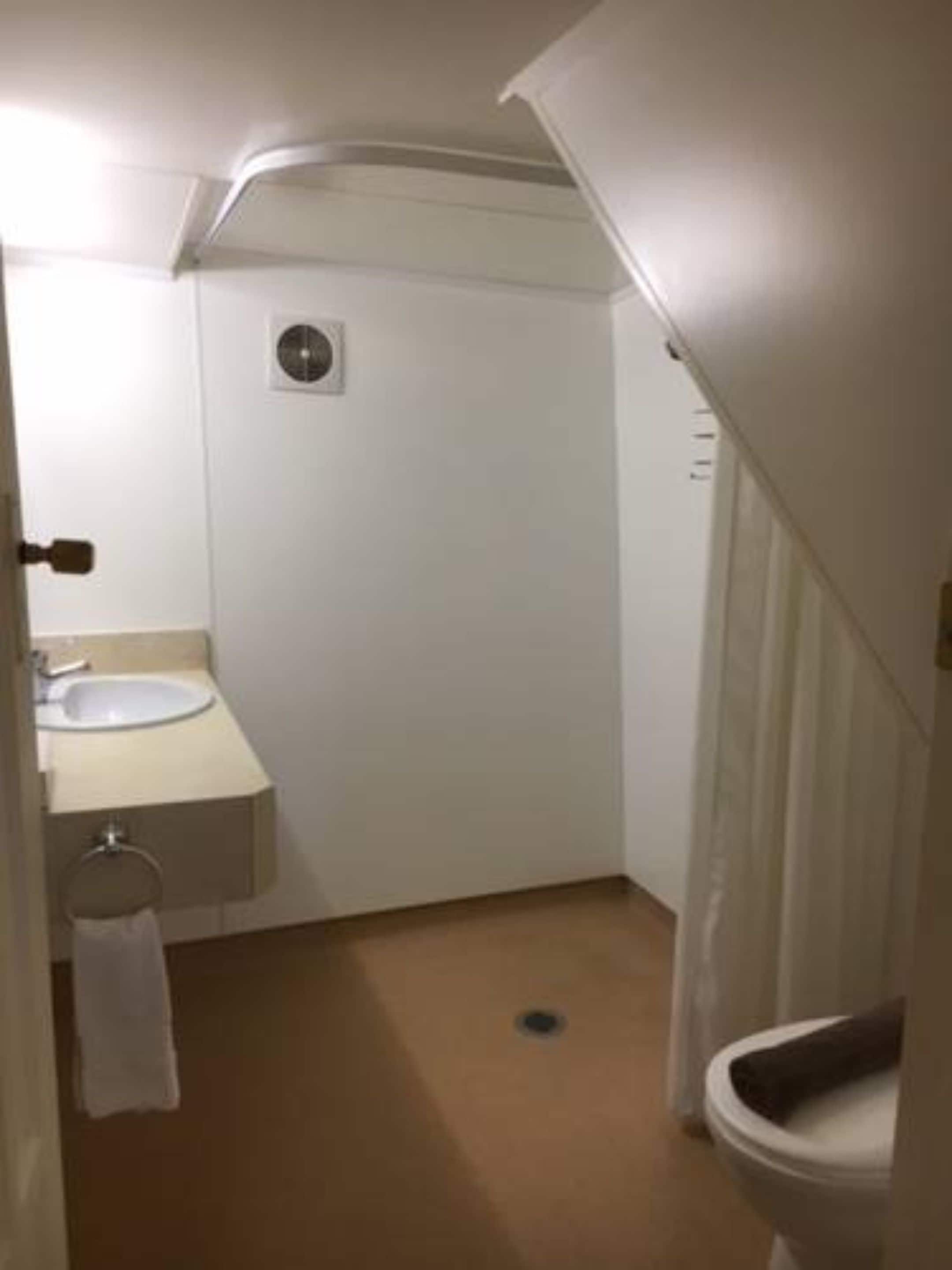 A small, compact bathroom with a sink, toilet, and a shower curtain.