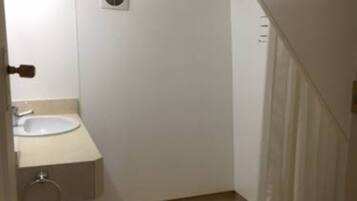 Un baño pequeño y funcional con lavamanos, inodoro y cortina de ducha.