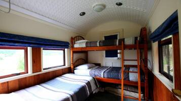 Een treincoupé met twee slaapplekken beneden en een slaapplek boven, houten wanden en een gestreept plafond.