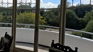 A room with large windows offering a view of a forested area. - Woodlyn Park (Waitomo Caves)