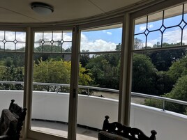 Quarto com grandes janelas proporcionando vista para uma área arborizada.
