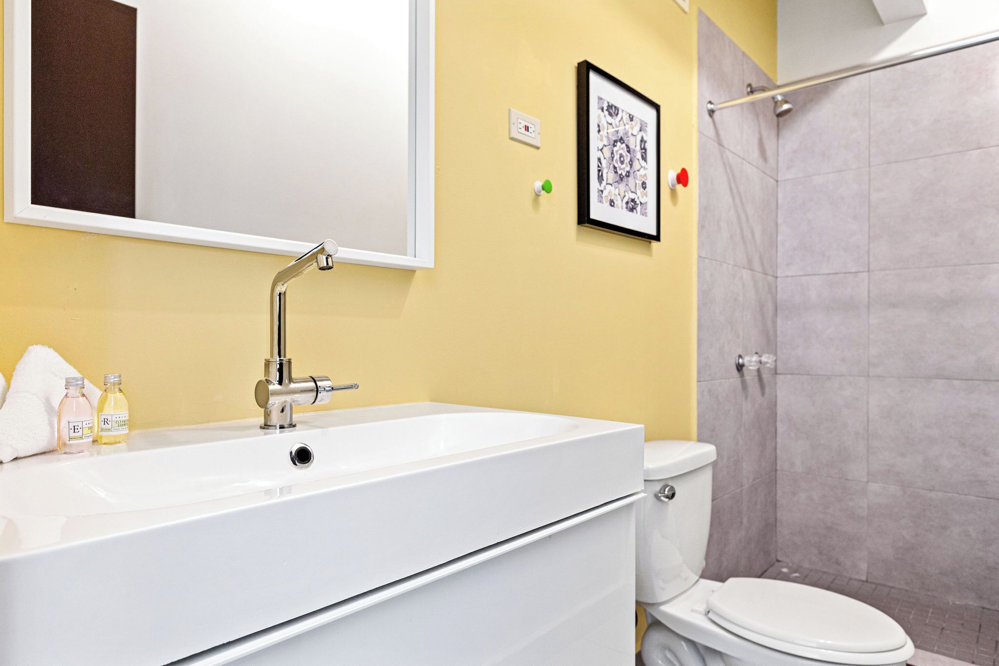 A bathroom with a white sink, a mirror, a toilet, and a shower area.