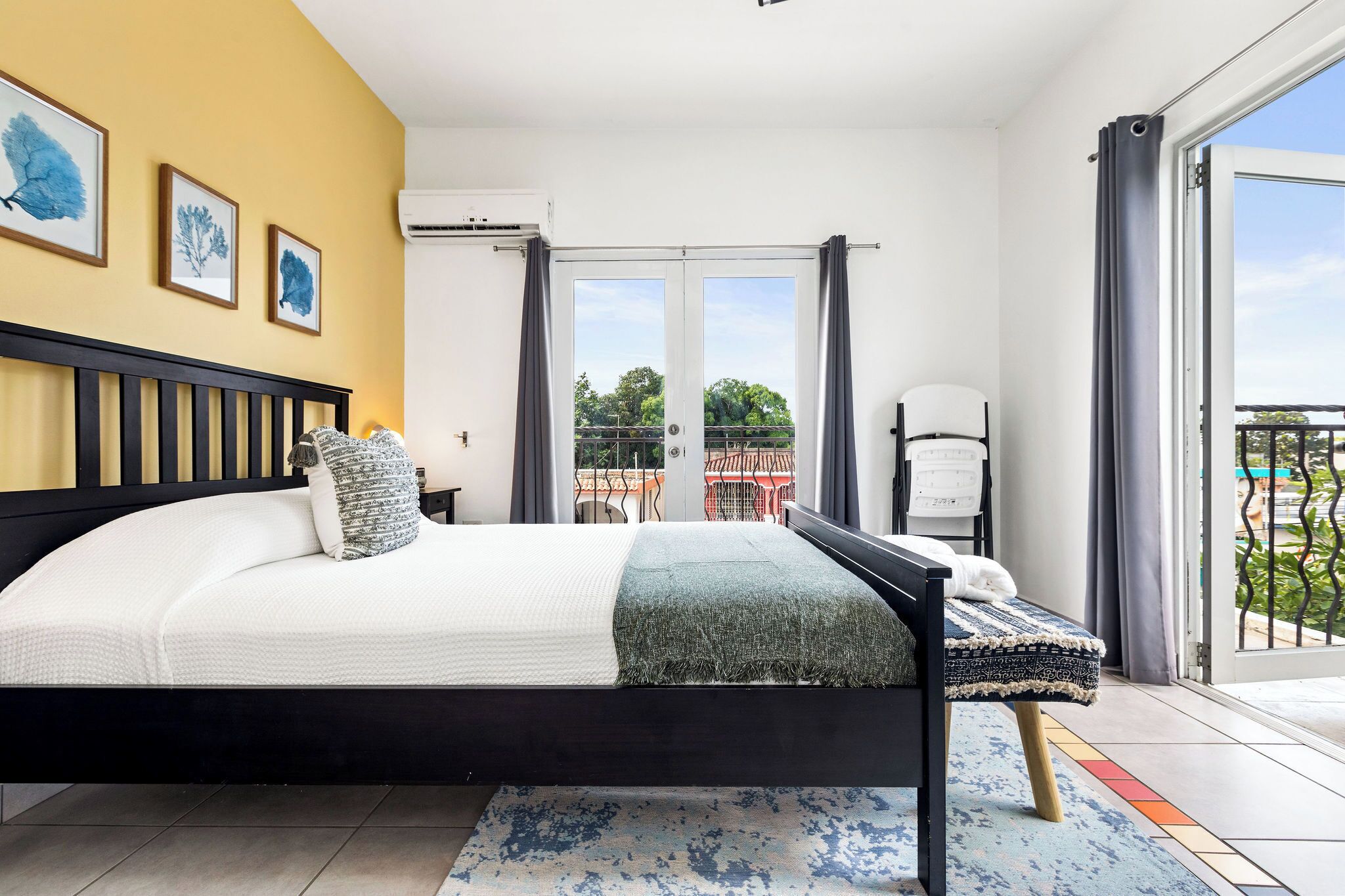 Un dormitorio con cama, una silla, un balcón y vistas a zonas verdes.
