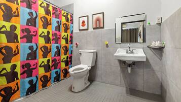 Un baño con cortina de ducha colorida, un inodoro, un lavabo y un espejo.