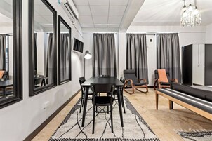 Una habitación moderna con una mesa de comedor, sillas, un sofá, un banco, un televisor y una araña.