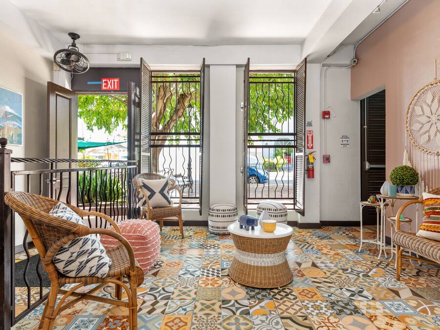 Um hall com móveis de vime, piso estampado e placa de saída.