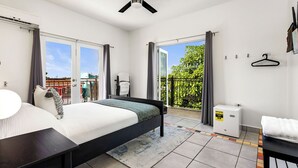A bedroom with a bed, a ceiling fan, a heater, and a view of the outside.