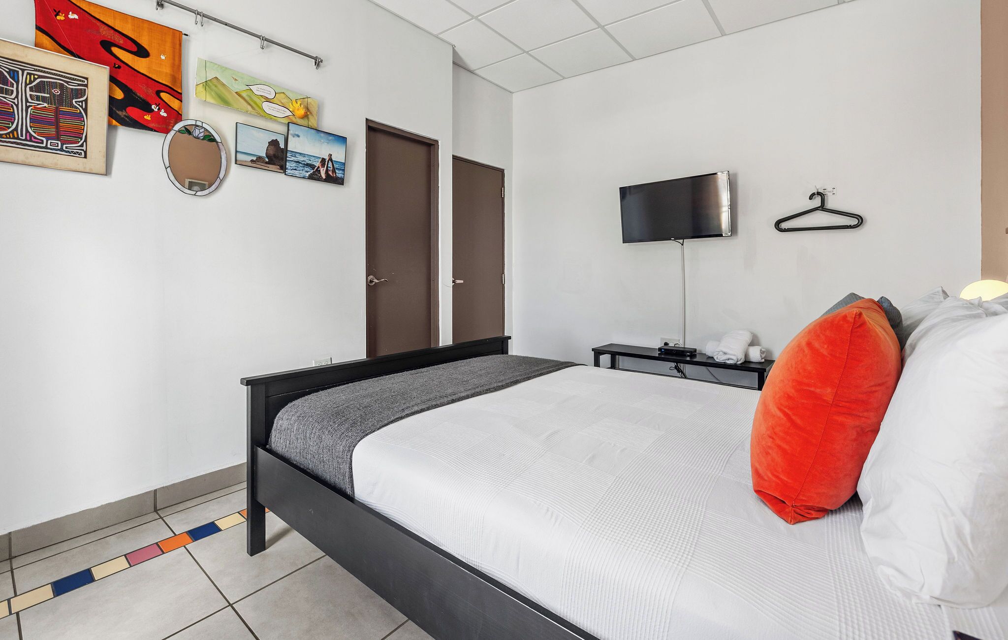 Ein Schlafzimmer mit einem Bett, einem Fernseher, einem Kleiderschrank und Bildern an der Wand.
