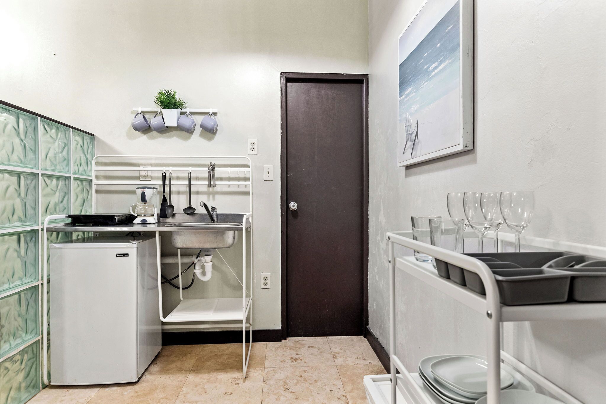 Una cocina compacta con refrigerador, lavamanos y una pequeña encimera.