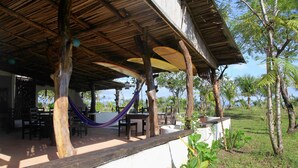 An outdoor covered patio with wooden beams, a hammock, and dining tables. - Hotel Hibiscus Garden / Jardin De Papos (Hicaco)