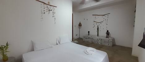 Un dormitorio con cama, ventilador de techo, cómoda y adornos en la pared.