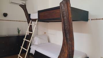 A bunk bed with a wooden ladder, a bedside table with a plant, and a white wall with an air conditioning unit.