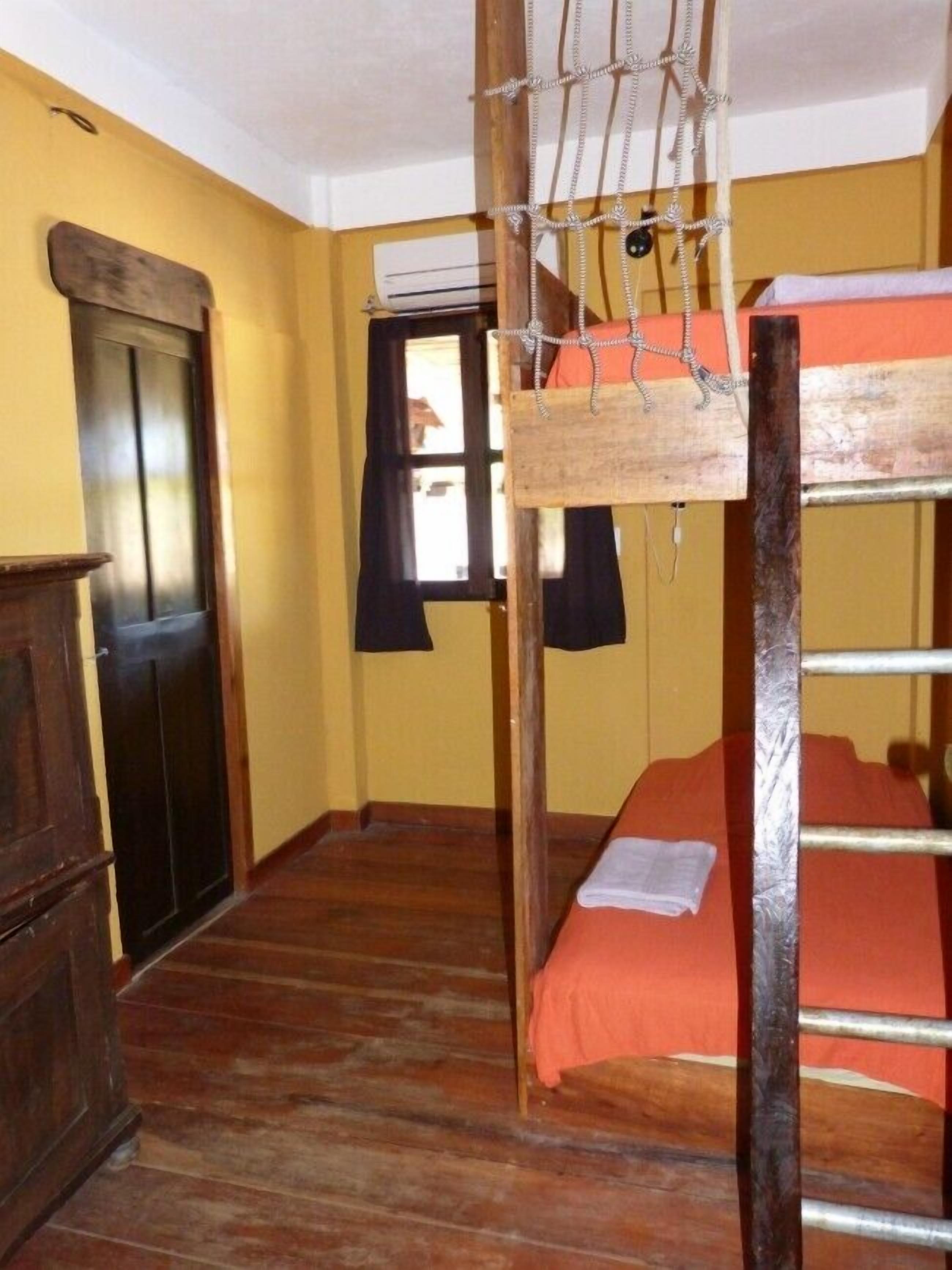 Una habitación con literas, un armario de madera y una puerta.