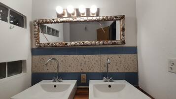 Casa de banho com duas pias, um espelho com luzes e azulejos estampados.