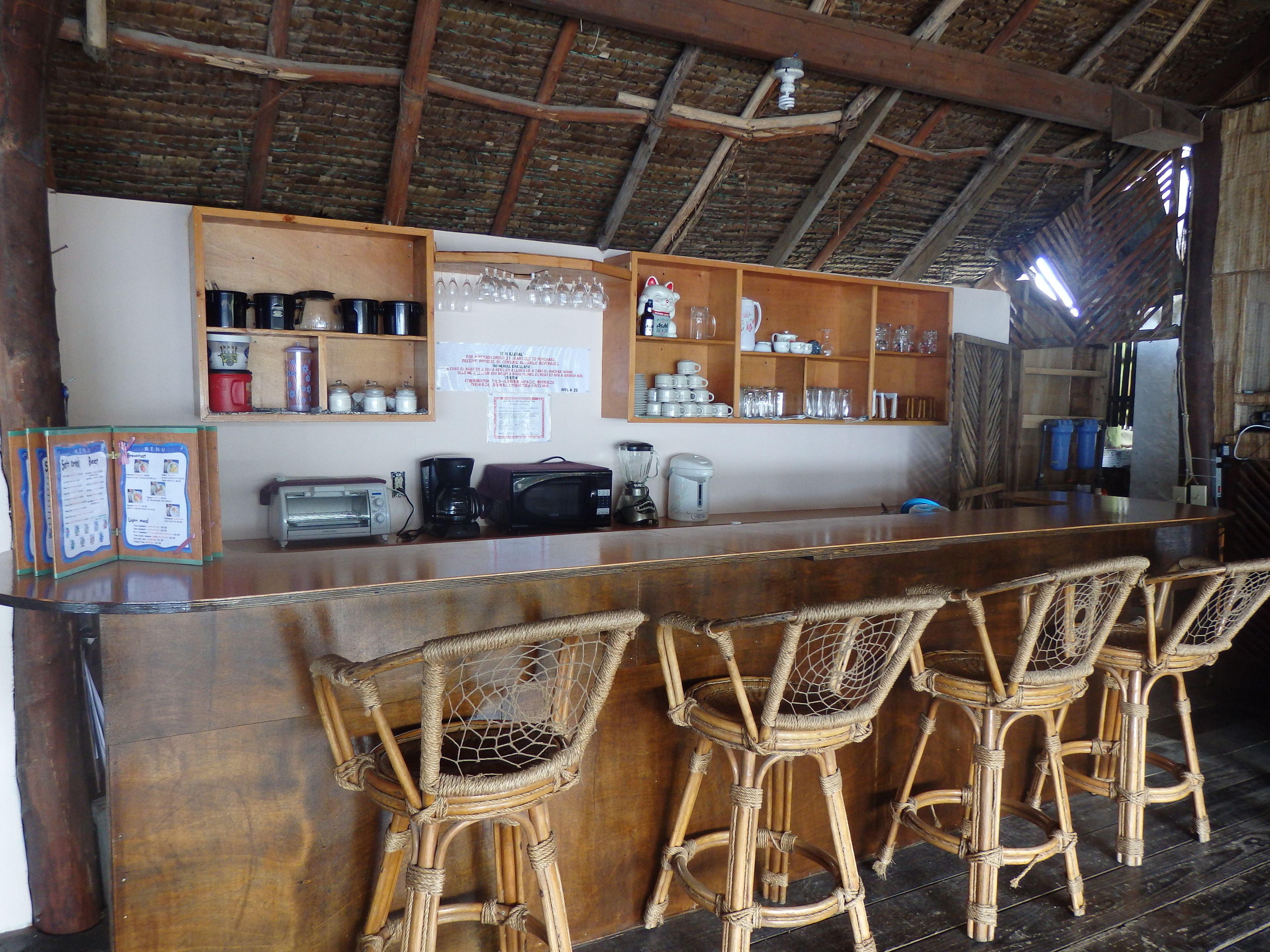 Eine Bar mit einem Holzboden, Korbstühlen und verschiedenen Küchengeräten.