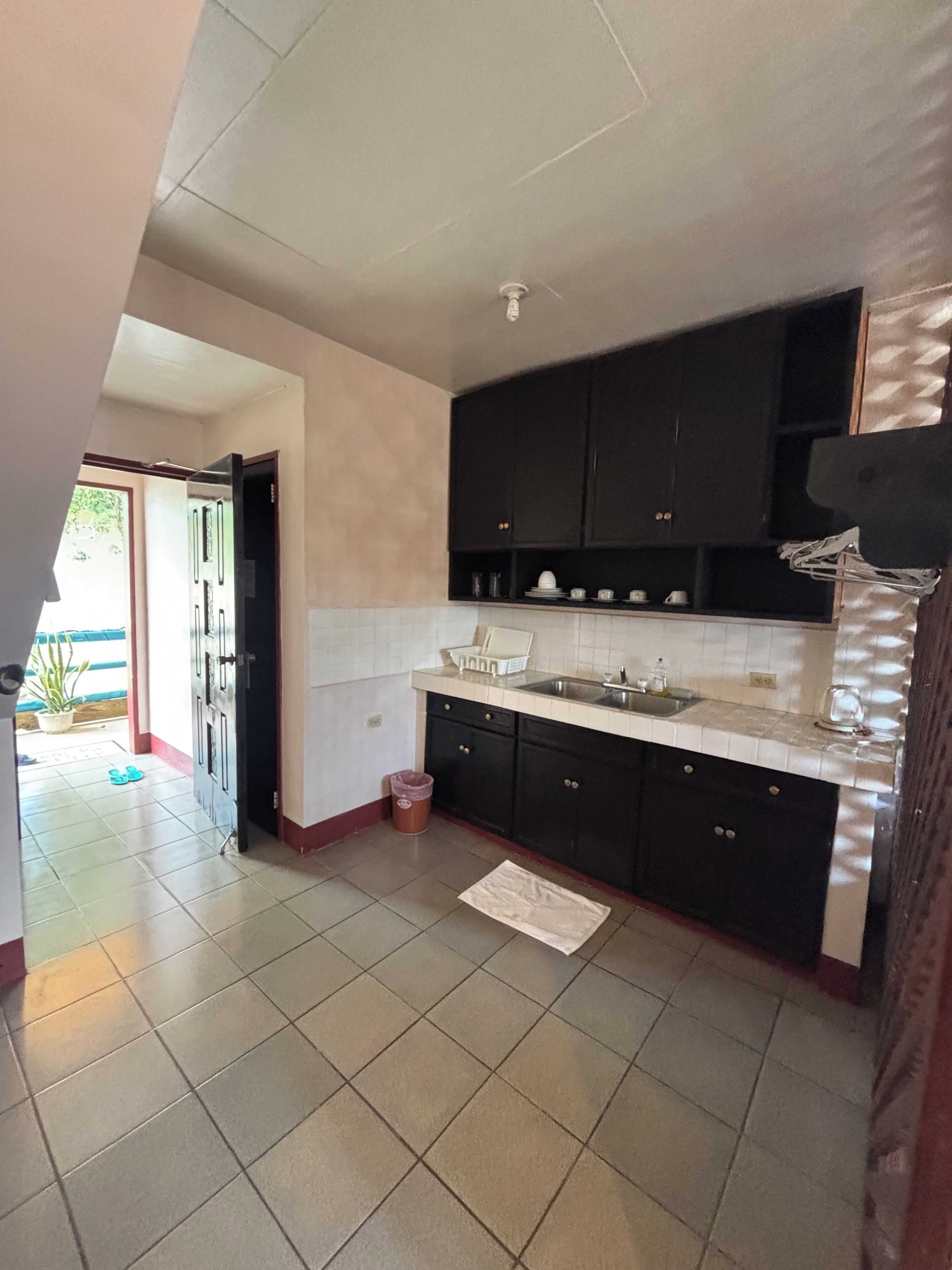 A kitchen with dark cabinets, a white countertop, and a tiled floor.