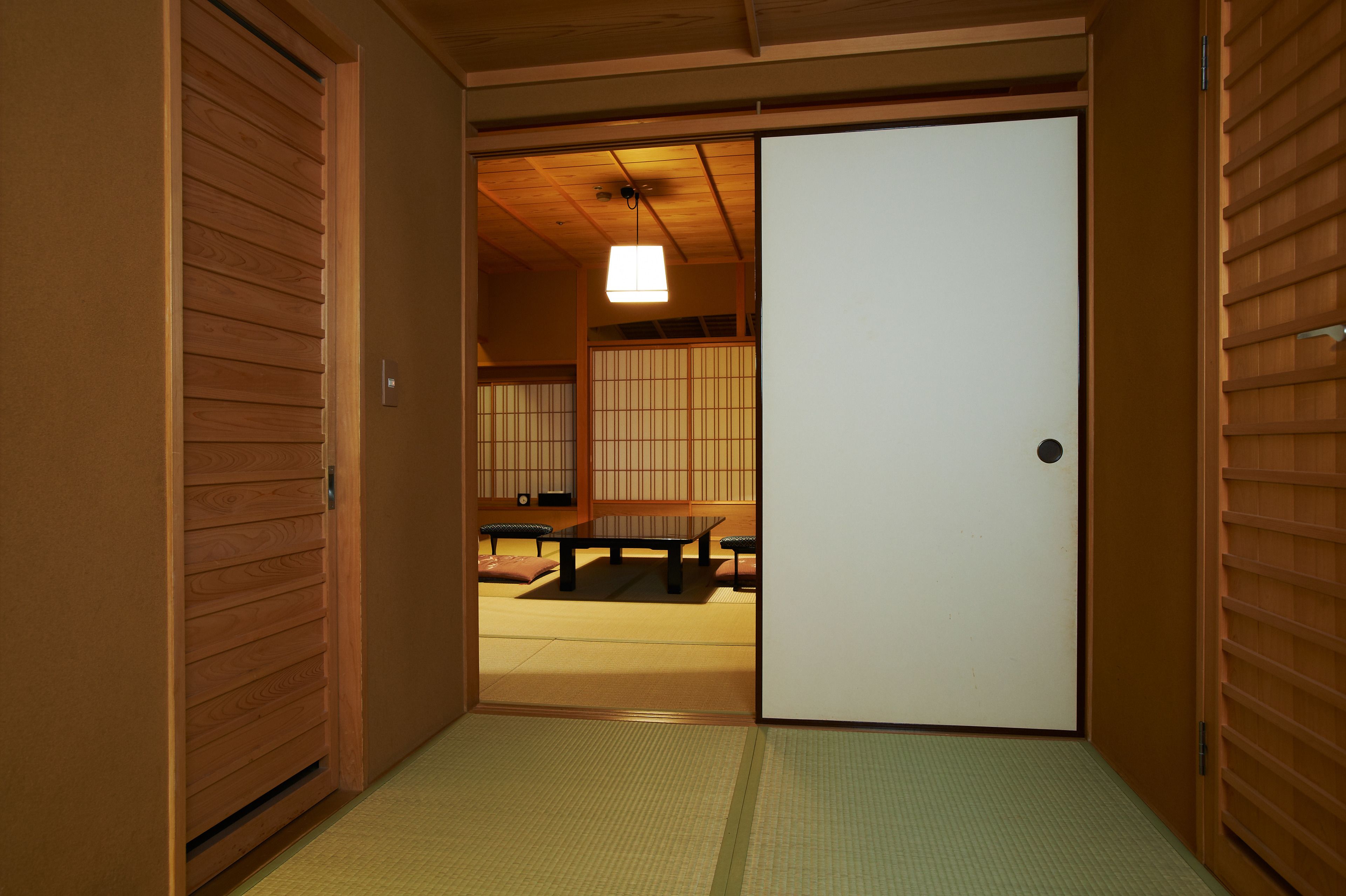 Een traditionele Japanse kamer met tatami vloeren, een schuifdeur en een lage tafel met kussens.
