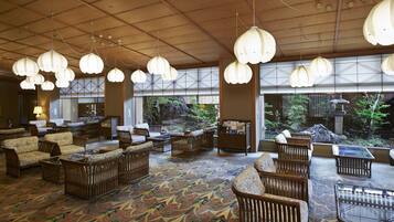 A spacious lobby with traditional furniture, large windows, and hanging light fixtures.