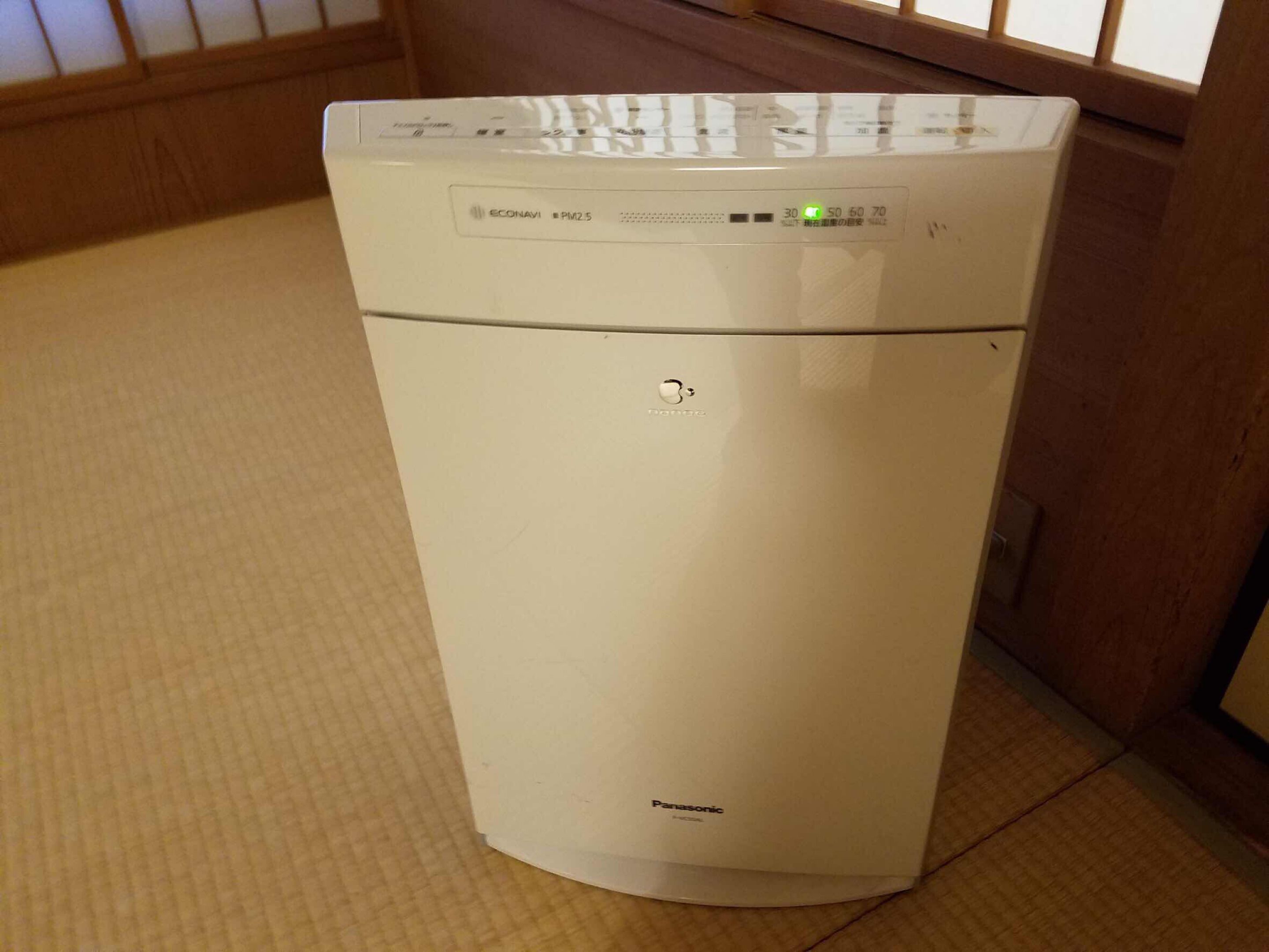 A white Panasonic PM2.5 air purifier in a room with tatami flooring.