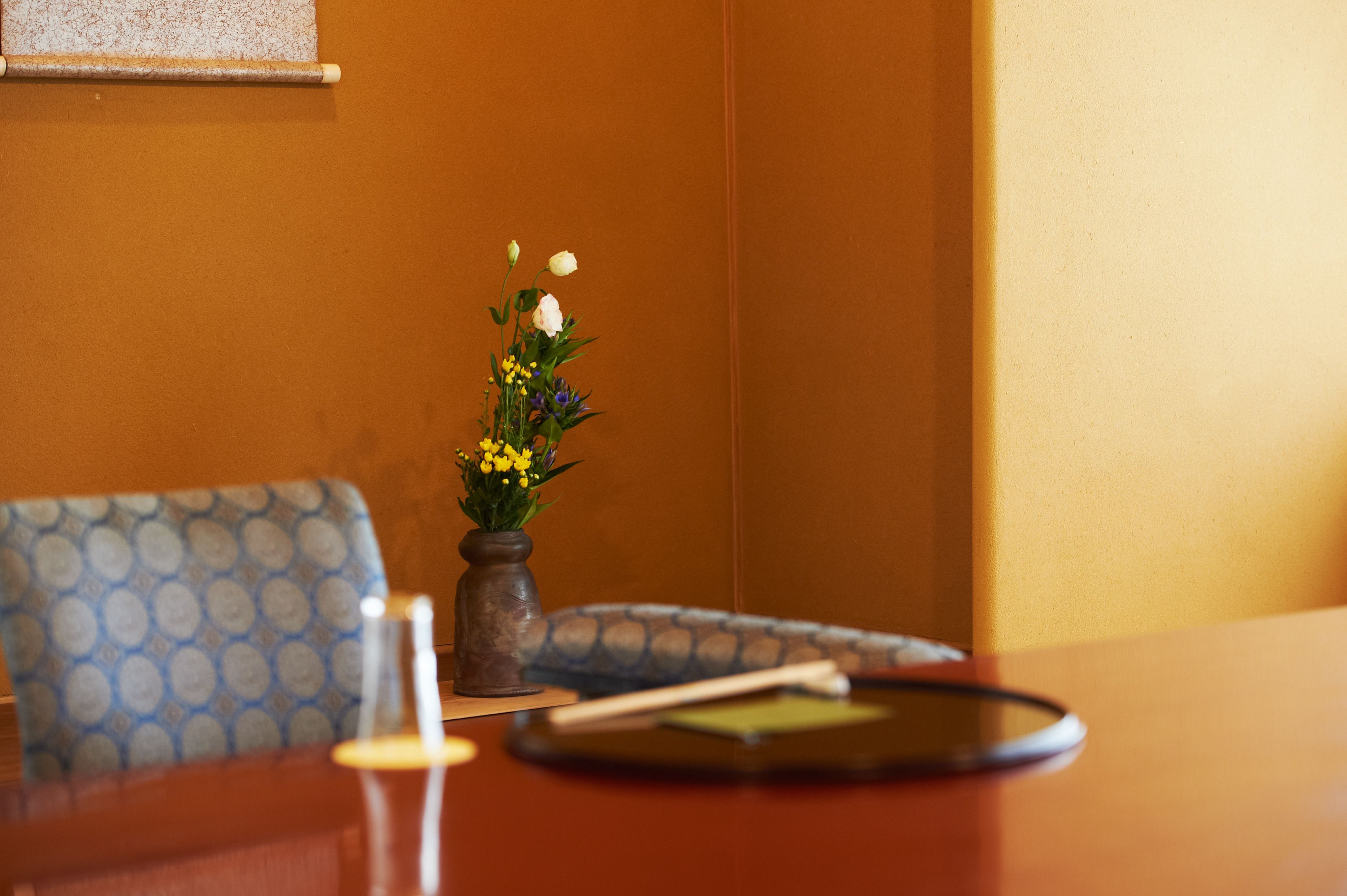 A dining table with a vase of flowers, a chopstick, and a black tray.