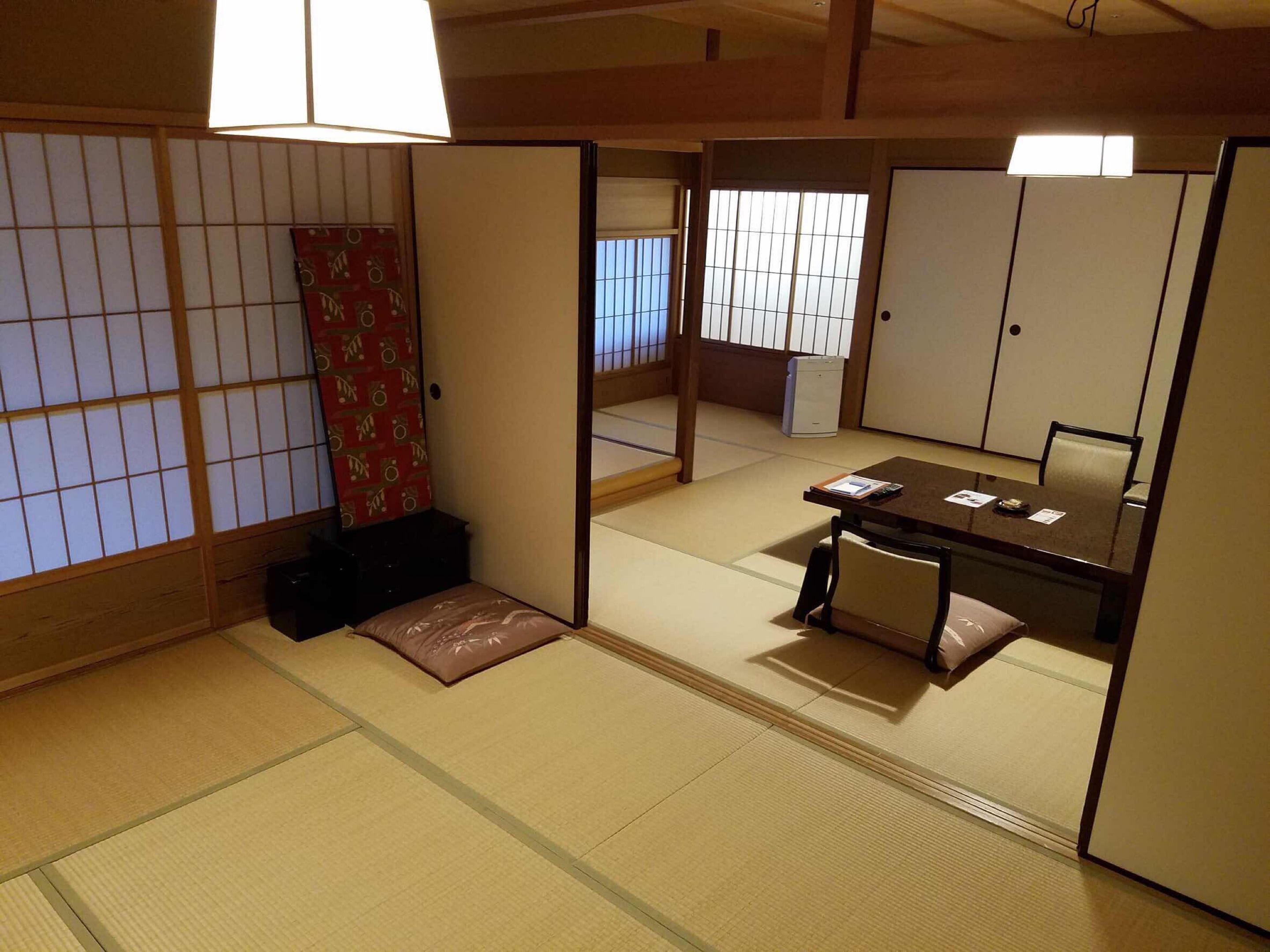 A traditional Japanese room with tatami flooring, a low table with cushions, and sliding doors.