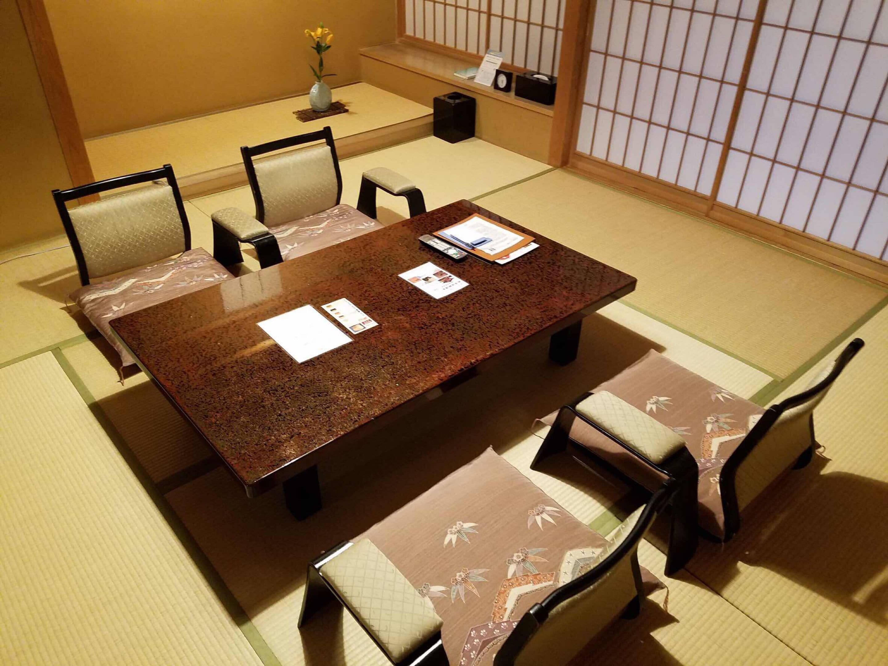 A traditional Japanese-style meeting room with tatami flooring, a low table, and four chairs.