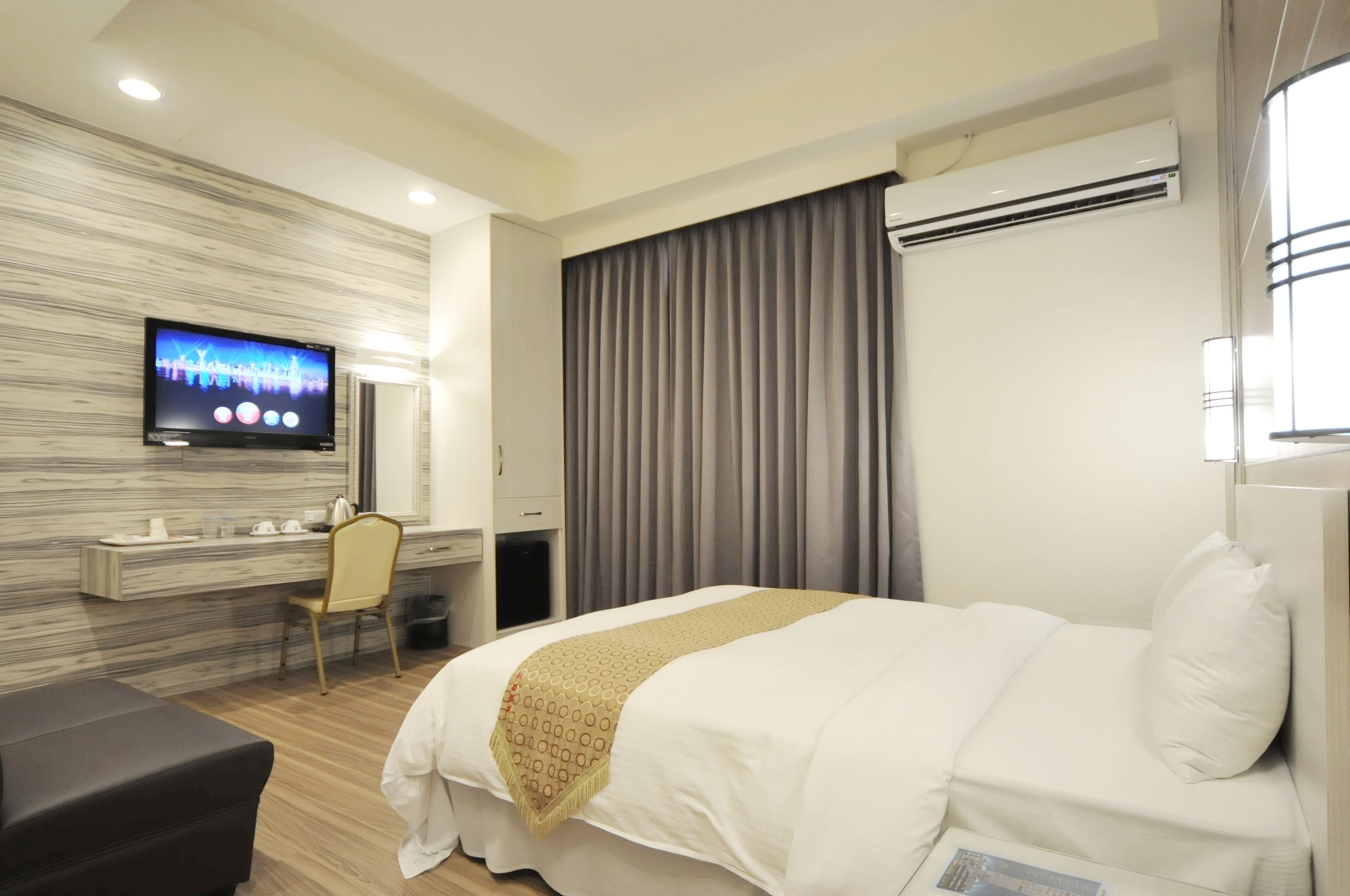Hotellihuone, jossa on sänky, työpöytä, tuoli, televisio ja ilmastointilaite.