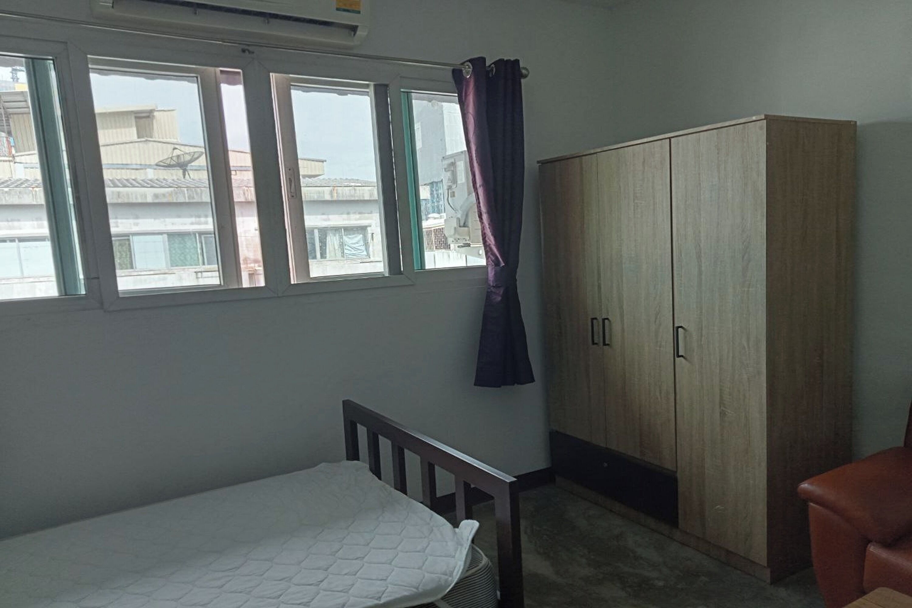 A bedroom with a single bed, a wardrobe, and a window with curtains.