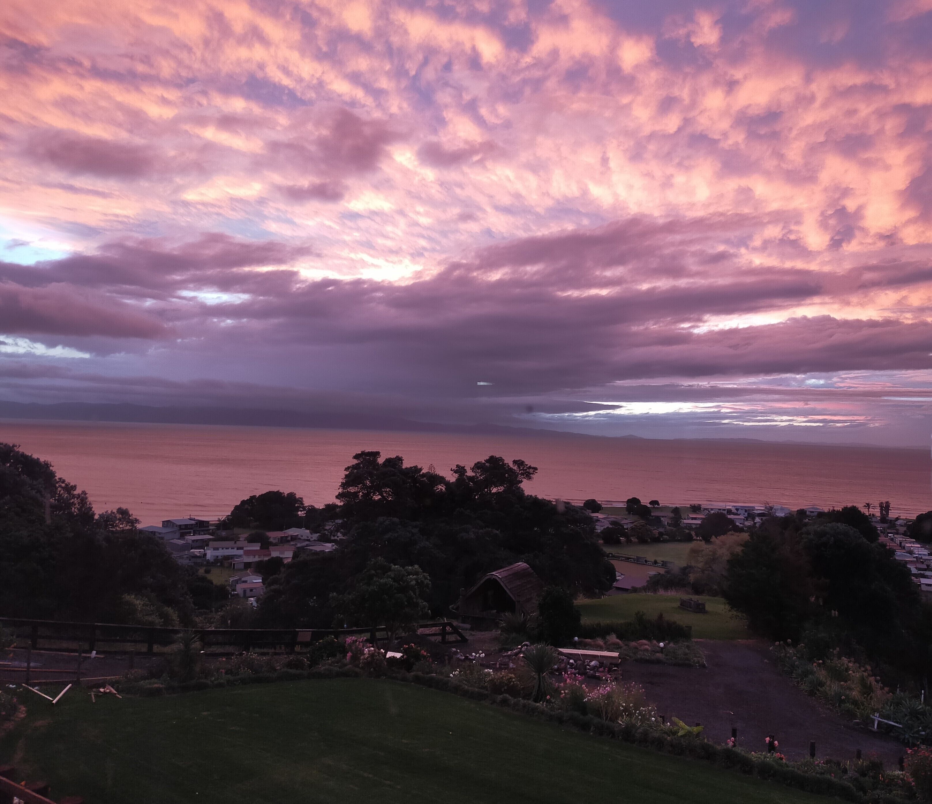 A coastal landscape with a view of the sea and a town in the distance.