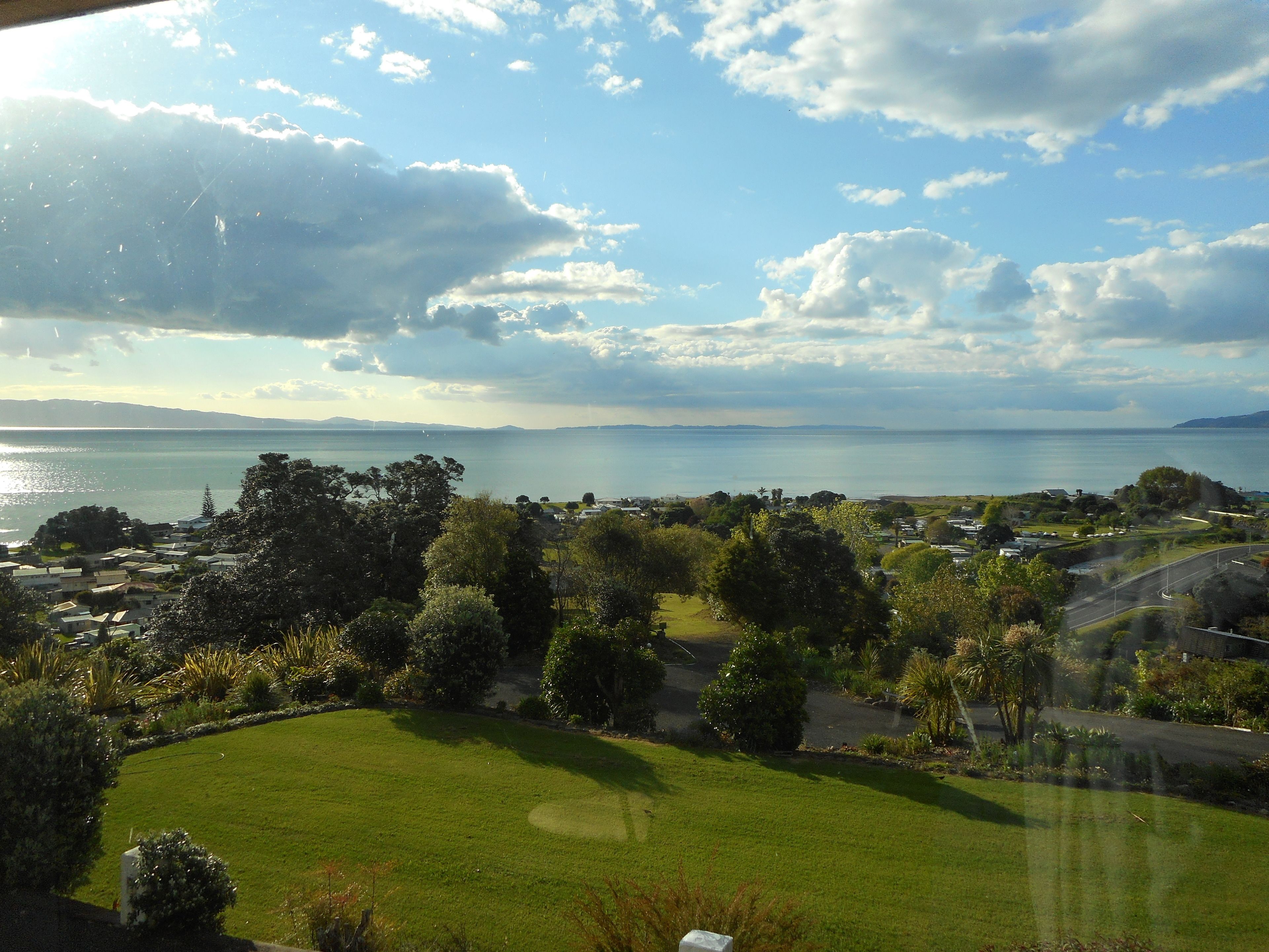 A coastal landscape with a golf course, houses, and a view of the sea.